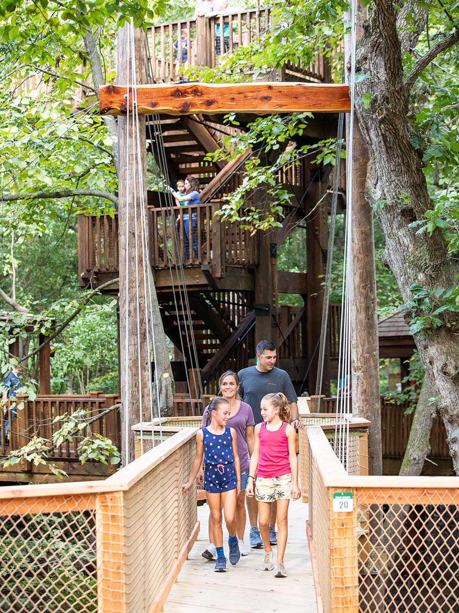 Family entering Treetop Village on wooden bridge at Arbor Day Farm